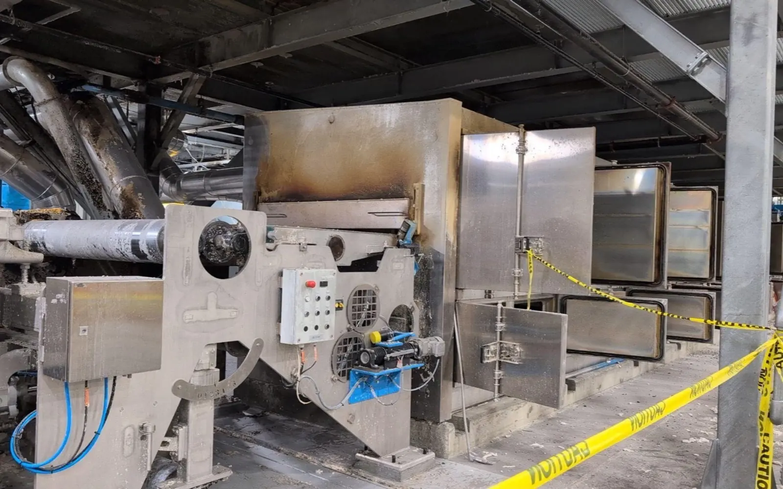 Industrial process machinery taped off after a fire, awaiting inspection and identification