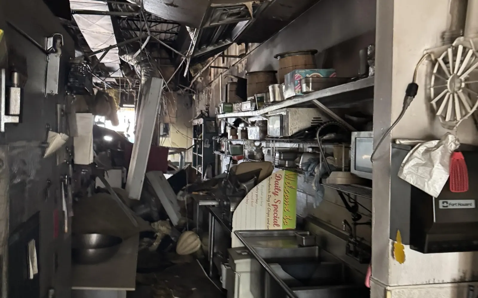 Commercial kitchen after a fire, with hood, prep line and stainless equipment smoke damaged